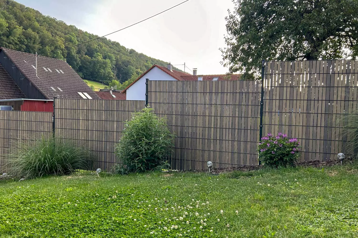 Großer Doppelstabmatten Zaun mit Sichtschutz aus Holz in grauem Farbton.